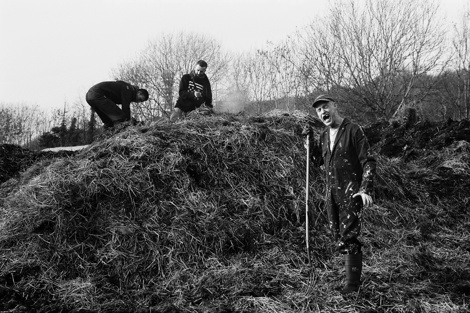 three folks digging over a pile of straw
